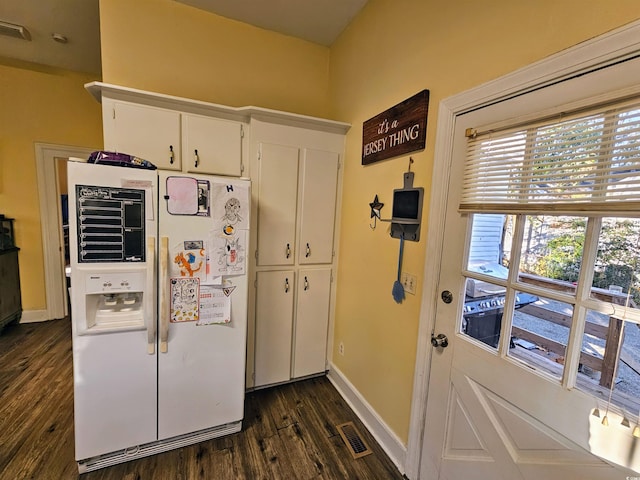 kitchen featuring dark wood-type flooring, white fridge with ice dispenser, and white cabinets