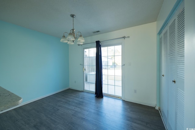 spare room featuring a chandelier, a textured ceiling, and dark hardwood / wood-style floors