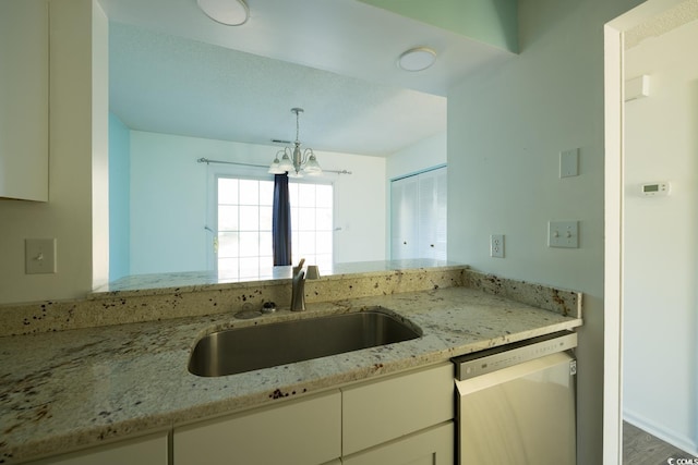 kitchen featuring light stone countertops, stainless steel dishwasher, sink, an inviting chandelier, and hardwood / wood-style floors