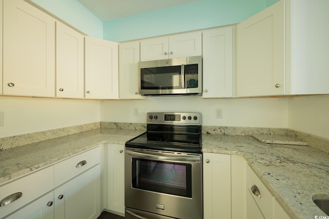 kitchen with light stone countertops, white cabinetry, and stainless steel appliances