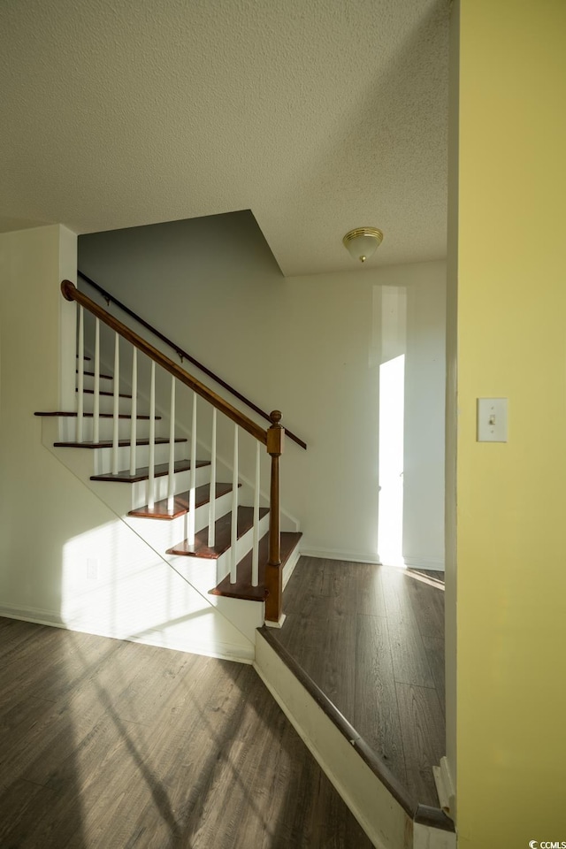 stairs featuring hardwood / wood-style floors and a textured ceiling