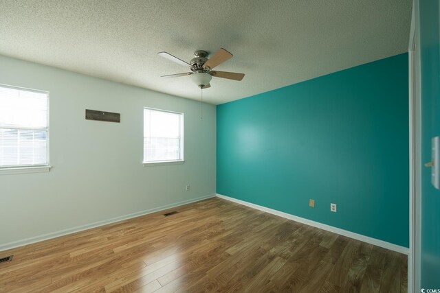 empty room with hardwood / wood-style flooring, ceiling fan, and a textured ceiling