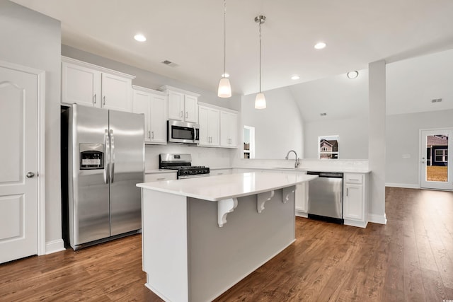 kitchen with stainless steel appliances, dark hardwood / wood-style flooring, kitchen peninsula, lofted ceiling, and white cabinets