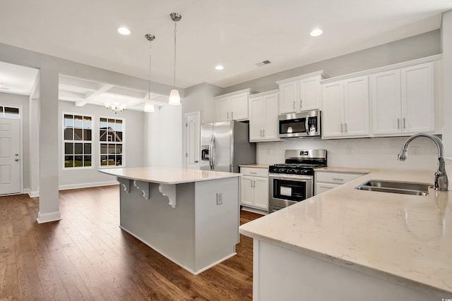 kitchen with appliances with stainless steel finishes, sink, beamed ceiling, white cabinets, and hanging light fixtures