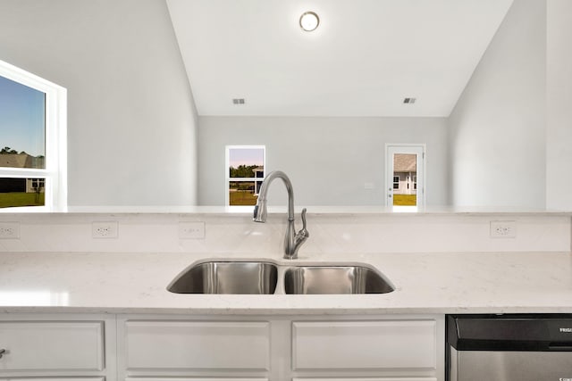 kitchen featuring dishwasher, light stone counters, plenty of natural light, and sink