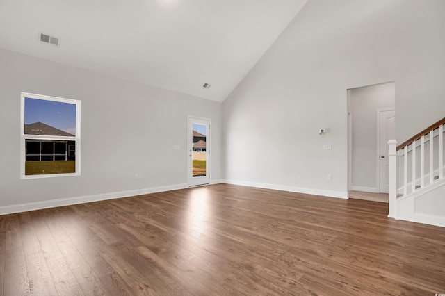 unfurnished living room with plenty of natural light, dark hardwood / wood-style flooring, and high vaulted ceiling