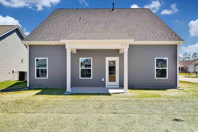 rear view of property featuring a lawn and cooling unit