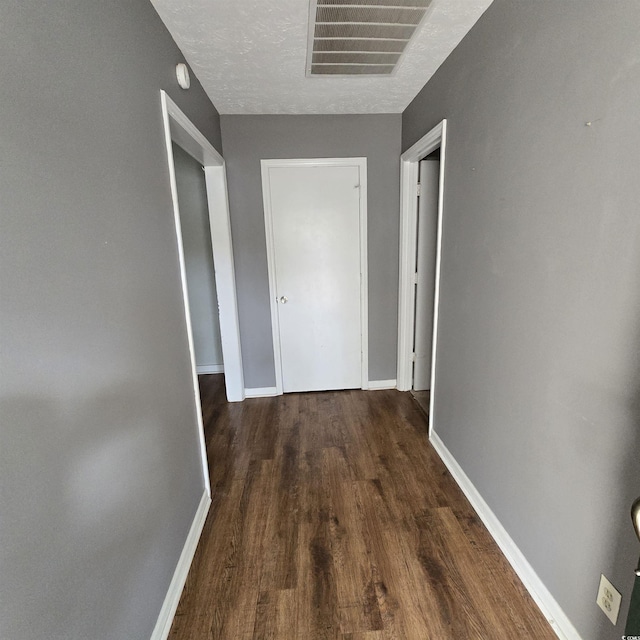 corridor featuring a textured ceiling and dark hardwood / wood-style floors