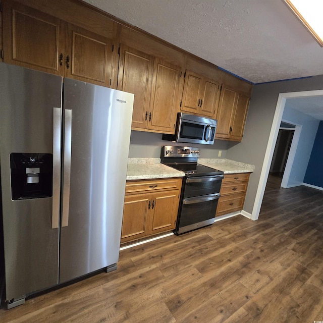 kitchen with a textured ceiling, dark hardwood / wood-style flooring, and stainless steel appliances