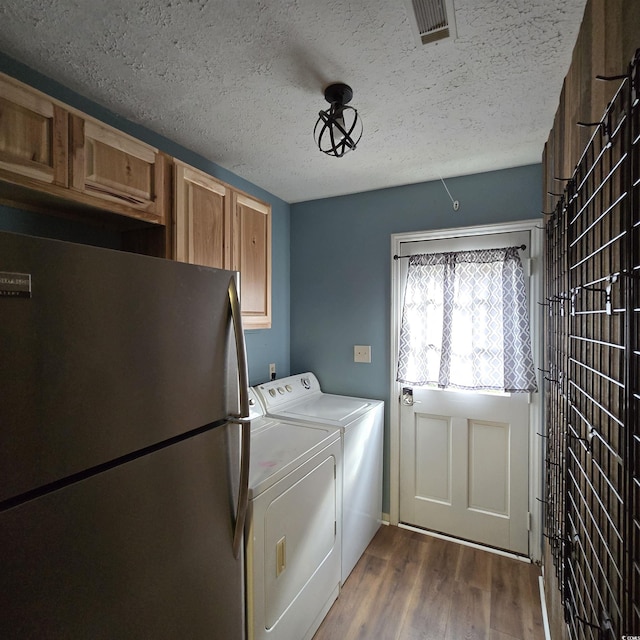 laundry room featuring cabinets, dark hardwood / wood-style flooring, washing machine and dryer, and a textured ceiling