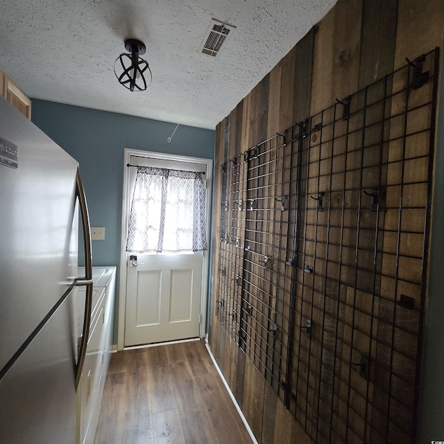 doorway with wood walls, dark hardwood / wood-style flooring, and a textured ceiling