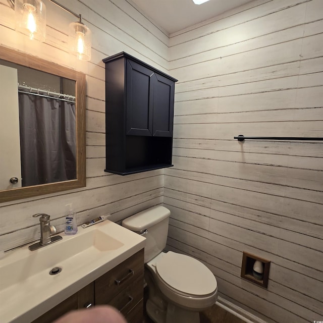 bathroom featuring vanity, toilet, and wood walls