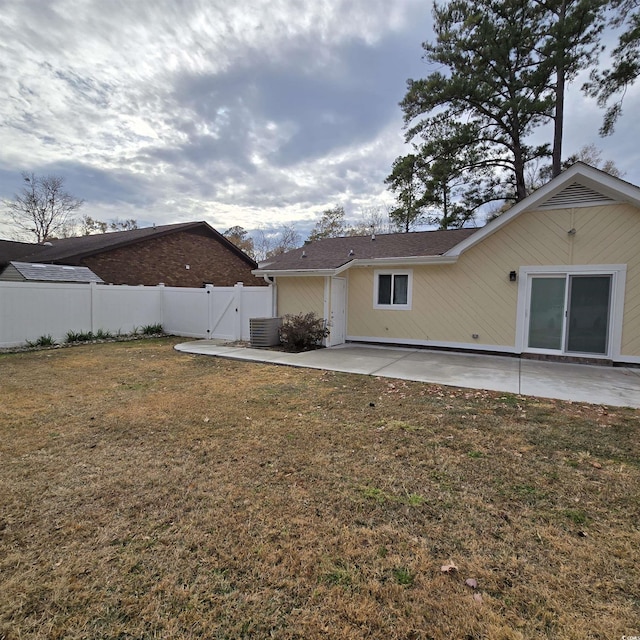 rear view of property featuring a patio area, a yard, and central AC