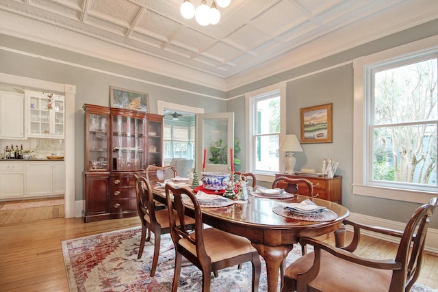 dining room with light wood-type flooring and crown molding