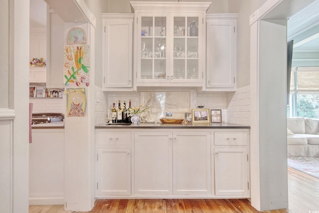 bar featuring white cabinets, decorative backsplash, and light hardwood / wood-style flooring