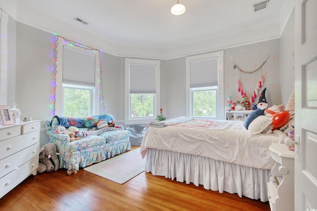 bedroom with multiple windows and hardwood / wood-style flooring