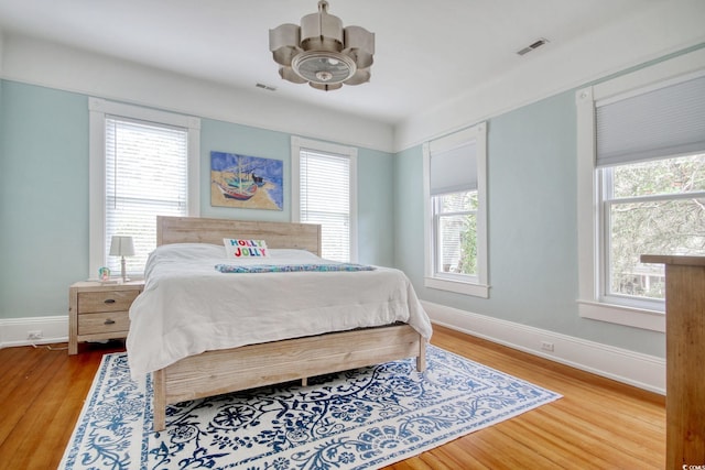 bedroom featuring multiple windows, ceiling fan, and hardwood / wood-style flooring