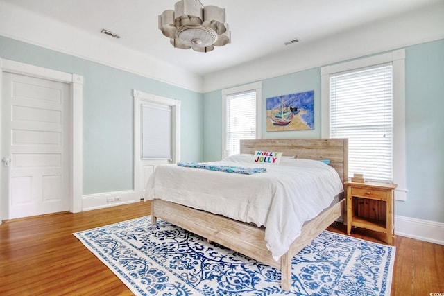 bedroom with ceiling fan, wood-type flooring, and multiple windows