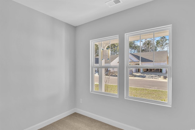 carpeted spare room featuring baseboards, visible vents, and a wealth of natural light