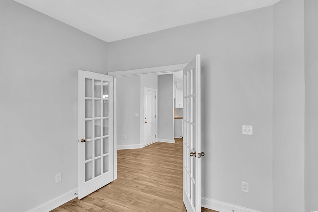 unfurnished room with french doors, baseboards, and light wood-style floors