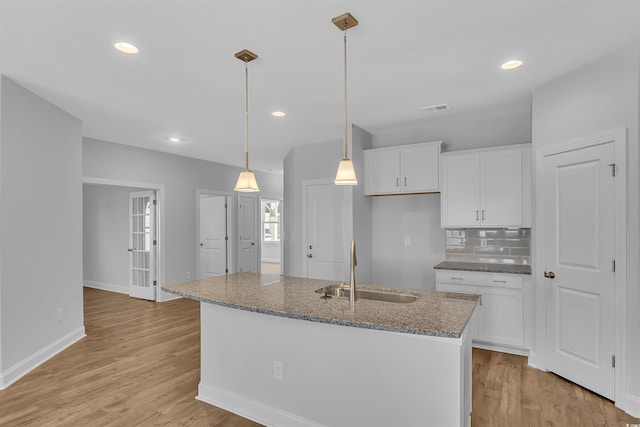 kitchen with white cabinetry, light wood-type flooring, and a sink