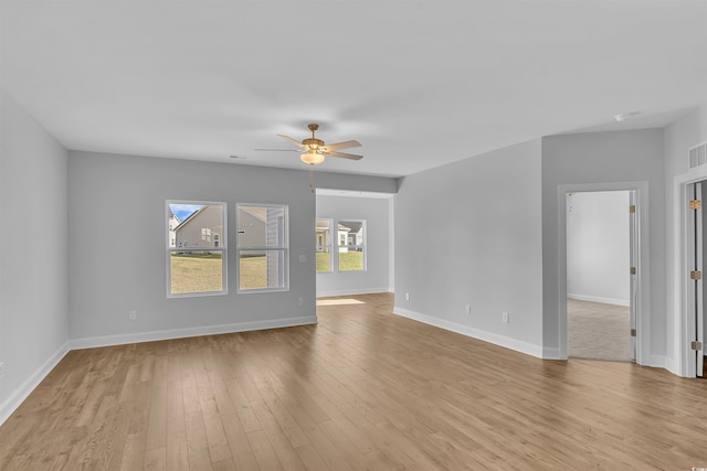 spare room featuring light wood finished floors, visible vents, baseboards, and ceiling fan