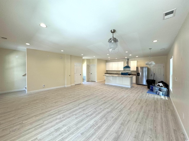 unfurnished living room featuring a chandelier and light hardwood / wood-style floors