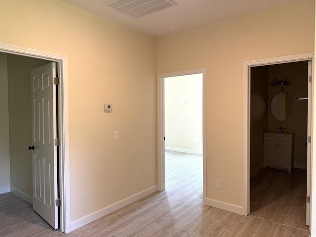 corridor with light hardwood / wood-style floors and sink