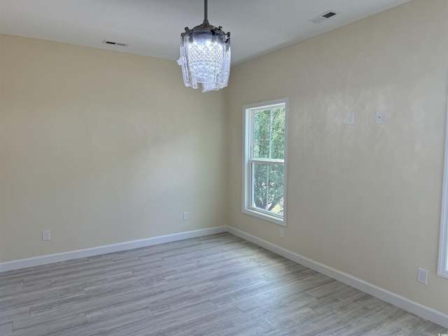 empty room featuring light hardwood / wood-style flooring and a notable chandelier