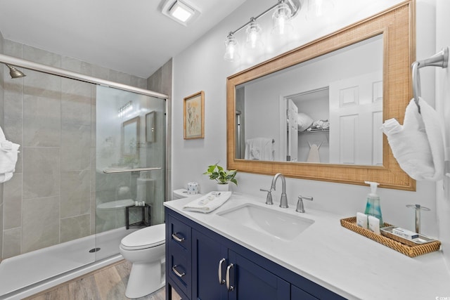 bathroom featuring vanity, hardwood / wood-style flooring, toilet, and walk in shower