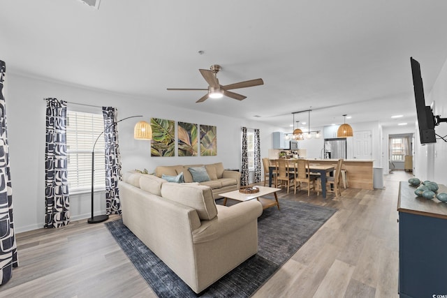 living room with wood-type flooring, ceiling fan, and a healthy amount of sunlight