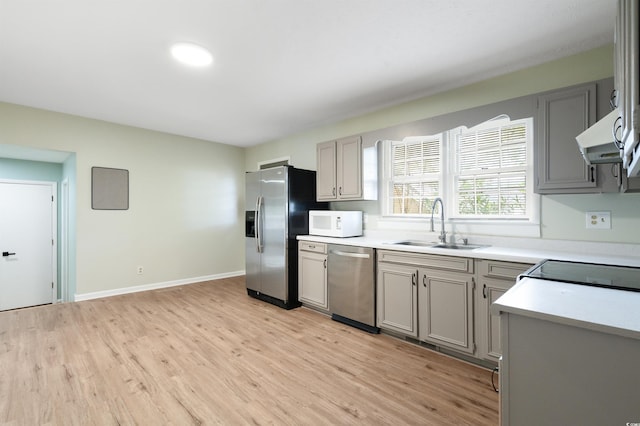 kitchen featuring gray cabinetry, sink, stainless steel appliances, ventilation hood, and light hardwood / wood-style floors