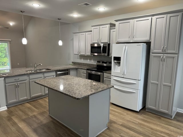 kitchen featuring kitchen peninsula, hardwood / wood-style flooring, decorative light fixtures, and appliances with stainless steel finishes