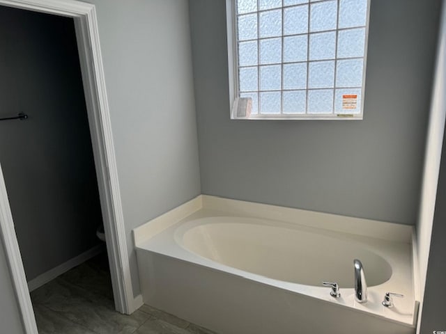 bathroom with tile patterned flooring, toilet, and a tub to relax in