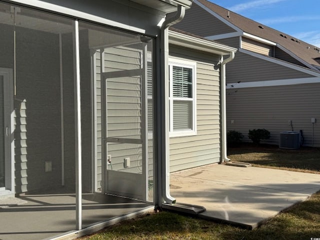 view of side of property with central air condition unit, a sunroom, and a patio