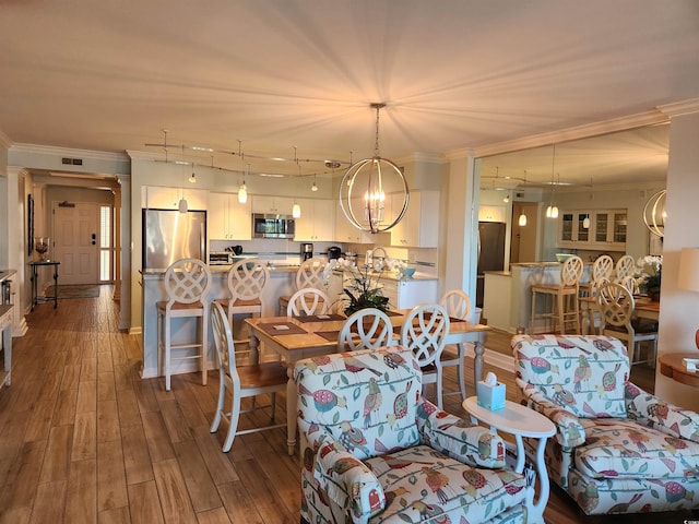 dining room with sink, hardwood / wood-style floors, a chandelier, and ornamental molding