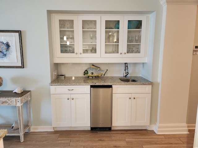 bar featuring light stone countertops, light hardwood / wood-style floors, white cabinetry, and sink