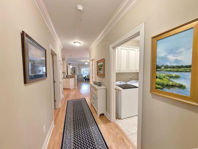 hallway with light hardwood / wood-style flooring, crown molding, and washing machine and clothes dryer