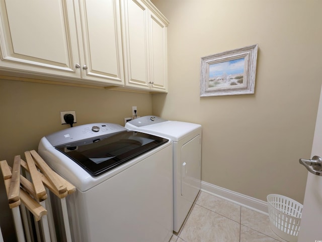 laundry room with light tile patterned flooring, cabinets, and washing machine and clothes dryer