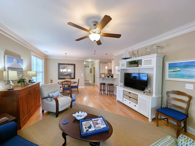 living room with ceiling fan with notable chandelier, light hardwood / wood-style floors, and crown molding