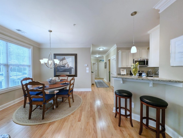 dining room with light hardwood / wood-style flooring, an inviting chandelier, and ornamental molding