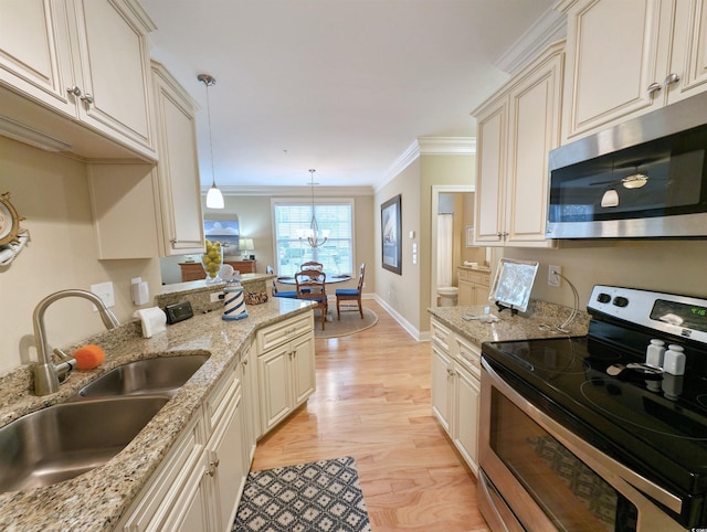 kitchen featuring pendant lighting, cream cabinetry, sink, and appliances with stainless steel finishes