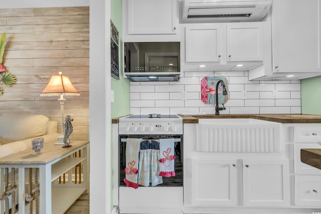 kitchen with sink, stove, white cabinetry, and backsplash