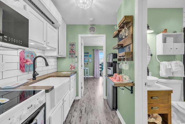 kitchen with sink, light hardwood / wood-style flooring, a textured ceiling, tasteful backsplash, and white cabinetry