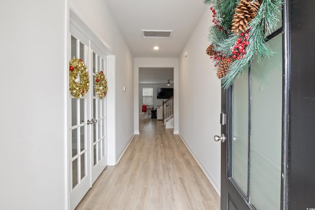 hallway with french doors and light hardwood / wood-style floors