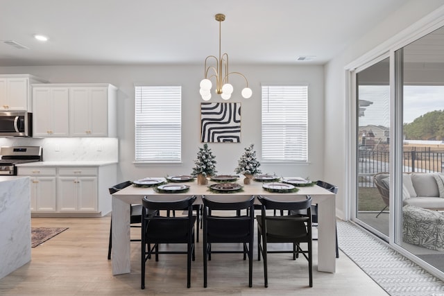 dining area featuring light hardwood / wood-style flooring and a notable chandelier