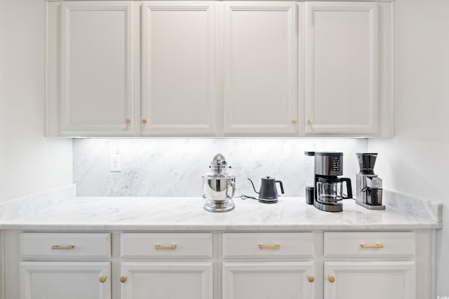 bar with light stone countertops, white cabinetry, and tasteful backsplash