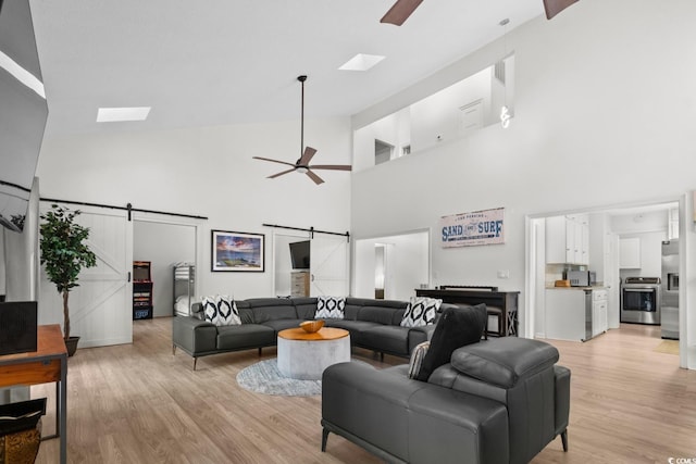 living room with a barn door, high vaulted ceiling, and light hardwood / wood-style flooring