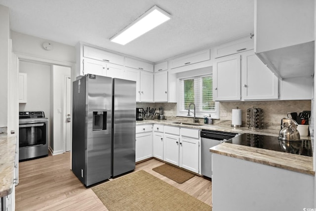 kitchen featuring decorative backsplash, appliances with stainless steel finishes, light wood-type flooring, sink, and white cabinets