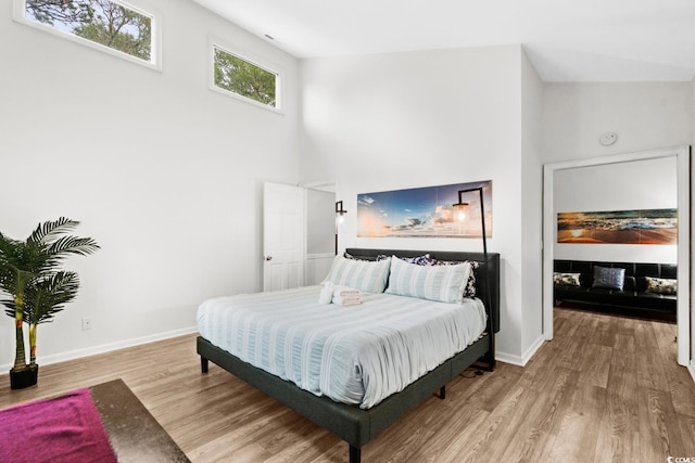 bedroom with hardwood / wood-style flooring and high vaulted ceiling